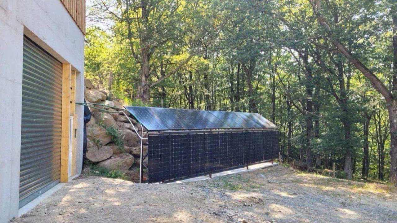 Rangée de capteurs solaires à air installés au sol le long d'un bâtiment agricole